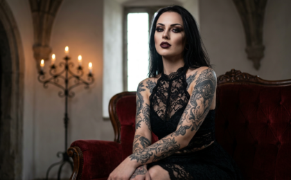 Devote Gothic Schlampen, die für alles offen sind: Eine sinnliche devote Gothic Schlampe mit dunklem Spitzen-Dessous und markantem Make-up blickt verführerisch in die Kamera.